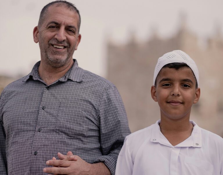 close up photo of a middle-aged man and young boy smiling at the camera