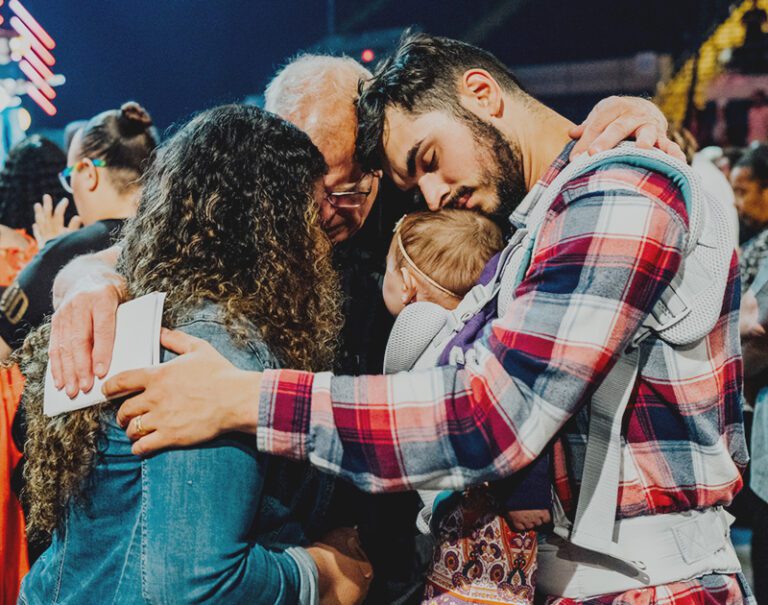 close up of three people hugging and quietly praying with one another