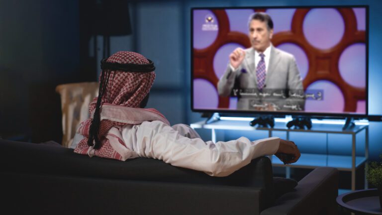 image of man wearing a traditional head covering watching Dr. Youssef on a television