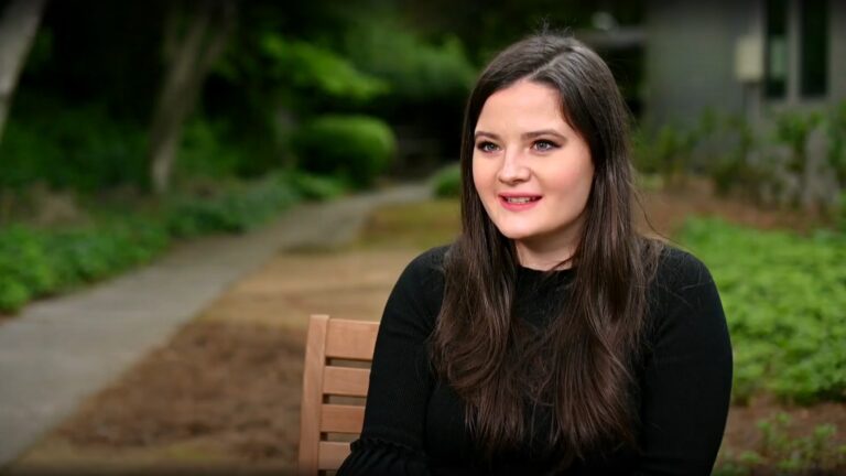 A young woman sits on a park bench