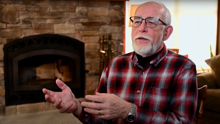 A man with beard and mustache gestures while speaking